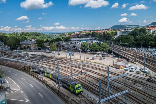 Blick auf einen grünen Zug der gerade in das Schienennetz in Bern einfährt